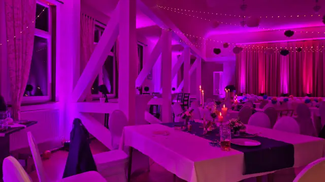 Saal am Abend mit Kerzen auf den Tischen und pinkem Licht